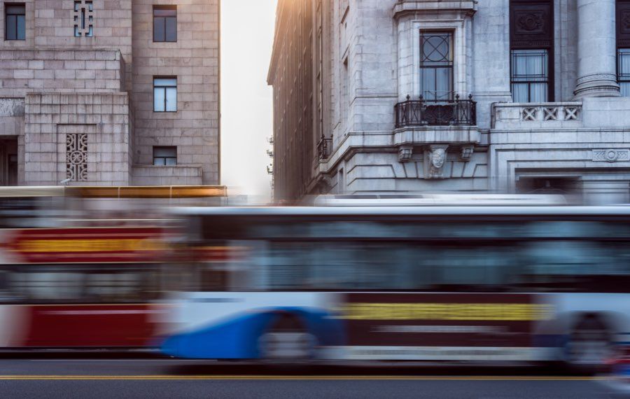 Avtobus v gibanju pred zgodovinskima kamnitima stavbama v mestnem središču